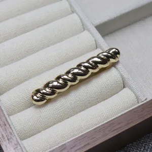 Close-up detail shot of the elegant gold twisted metal hair clip placed in a jewelry tray.