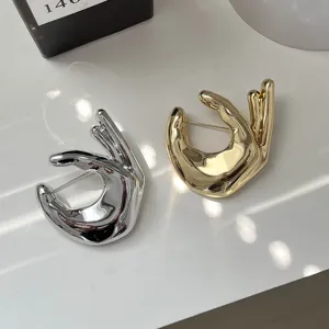 Chic metal hand gesture brooch in silver and gold, trendy minimalist sweater accessory.