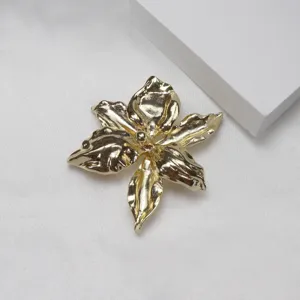 Detail view of a chic gold metal iris flower brooch, elegant 3D floral design for women.