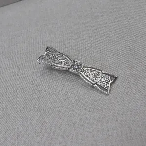 Detailed shot of a vintage silver-colored filigree bow hair clip with intricate patterns.