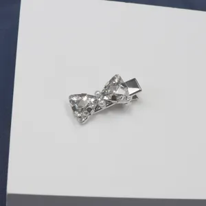 Detailed view of rhinestone bow hair clip, shiny crystal and pearl accents on metal clip.