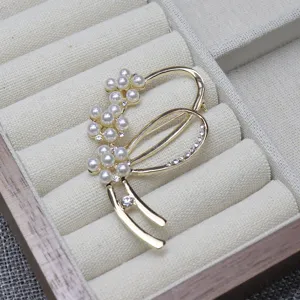 Close-up detail shot of elegant gold-toned pearl and rhinestone brooch, perfect for sweaters and suits.
