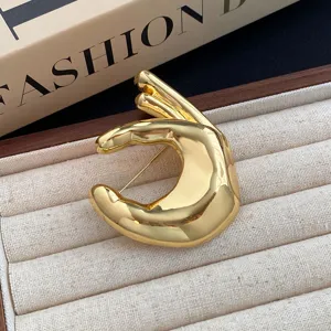 Gold metal hand gesture brooch minimalist chic sweater accessory fashion jewelry piece.