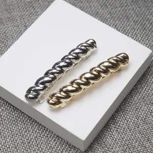 Detailed view of silver and gold twisted metal spring hair clips on white display stand.