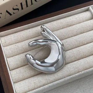 Silver metal hand gesture brooch, minimalist design apparel accessory for sweaters and coats.