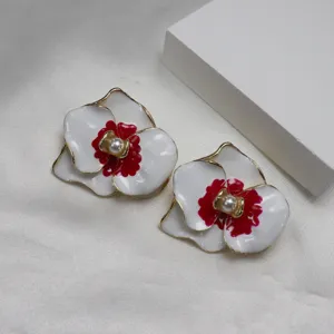 Detailed close-up shot of red and white enamel flower earrings brooch with central pearl accent.