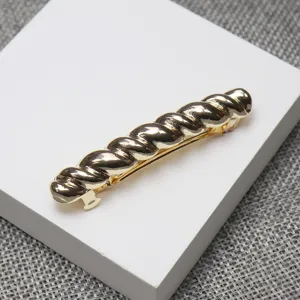 Gold twisted hair barrette detail shot, elegant small metal spring clip for women's hairstyles.
