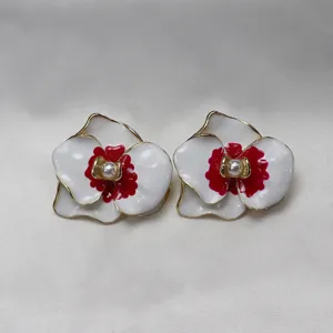 Elegant enamel moth orchid flower stud earrings with pearl center and gold trim details.