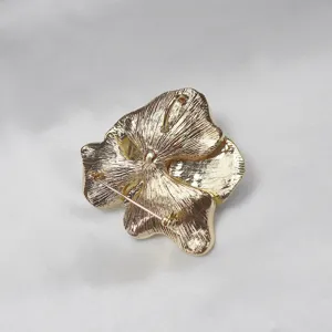 Gold flower brooch back detail showcasing secure pin clasp and versatile necklace pendant loop.