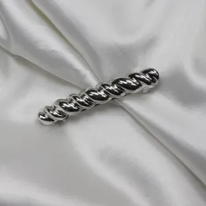 Detailed close-up shot of a stylish silver twisted hair clip barrette on white silk cloth.