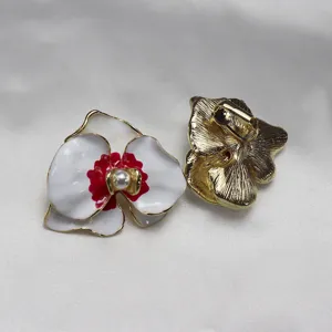 Detailed close-up view of vintage enamel orchid flower earrings featuring pearl and gold trim.