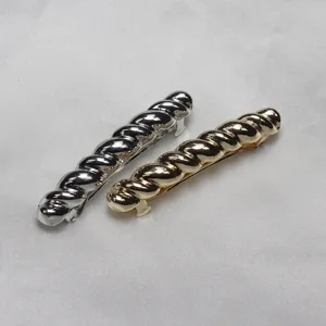 Metal twisted hair clip detail, spring clip design, shiny metallic finish, elegant accessory.