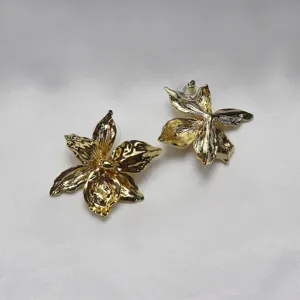 Detailed view of gold metal iris flower earrings, modern minimalist style jewelry piece.