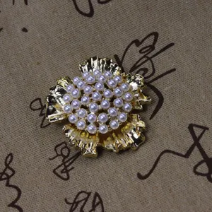 Gros plan détaillé de la broche fleur dorée vintage avec des perles au centre, bijou élégant.