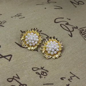 Vue détaillée de boucles d'oreilles vintage dorées en perles de fleurs avec pétales texturés.