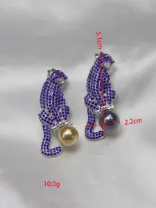 Close-up detail of vintage blue rhinestone leopard brooch holding pearl, sparkling crystal design.