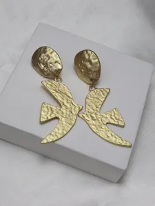 Close-up detail of retro gold textured swallow bird designer earrings, exquisite metal craft.