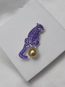 Exquisite rhinestone panther brooch detail shot featuring purple crystals and golden pearl accent.