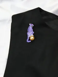 Close-up of a vintage panther brooch with blue crystals and a golden pearl detail.