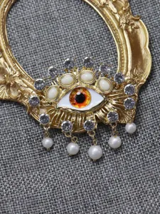 Exquisite evil eye brooch detail showing sparkling rhinestones and delicate pearl pendants.