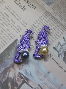 Detailed view of luxury crystal leopard brooch featuring sparkling purple rhinestones and pearl pendant.