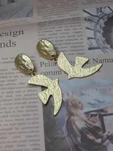 Close-up detail view of elegant gold finish hammered dove earrings with unique textured metal design.