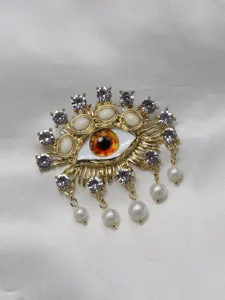 Detail closeup of the baroque pearl rhinestone devil eye brooch metal fashion jewelry accessory.