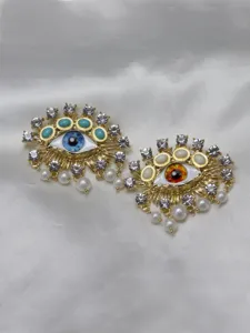 Detail shot of baroque evil eye brooches with sparkling crystals and hanging pearls closeup.