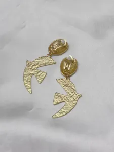 Close-up detail display of gold-toned textured flying bird motif clip-on earrings.