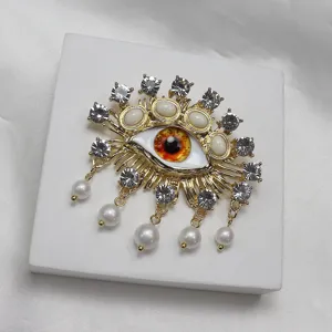 Exquisite evil eye brooch with dazzling rhinestones and pearl drops, fashionable gold alloy corsage for women.