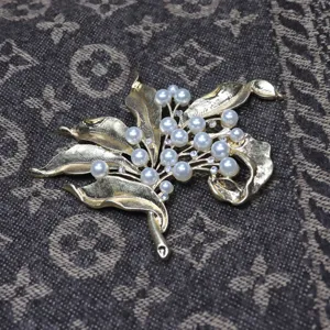 Vintage floral pearl rhinestone brooch detail, elegant gold tone leaf clothing accessory item.