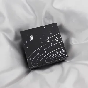 Boîte cadeau carrée noire avec design cosmique argenté, détail d'emballage de bijoux élégant.