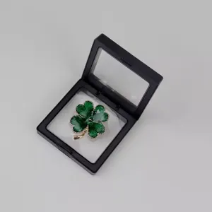 Vue détaillée rapprochée d'un bijou trèfle à quatre feuilles vert dans une boîte.