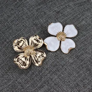 Vintage metal four-leaf clover flower brooch, elegant gold and white enamel design.