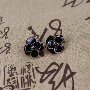 Detailed shot of black and gold camellia flower stud earrings with elegant retro enamel design.