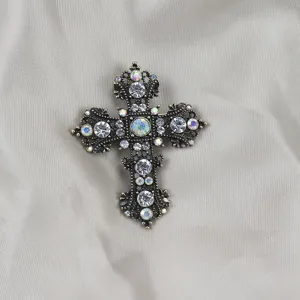 Gedetailleerde close-up van een prachtige vintage kruisbroche met glinsterende strass en antiek goud.