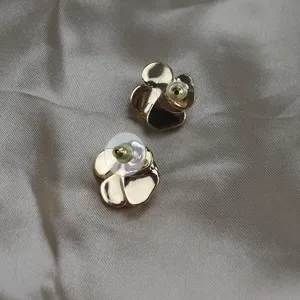 Gold camellia flower stud earrings detail view showing silver posts and secure ear backs.