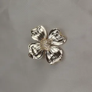 Close-up detail of vintage gold metal four-leaf clover flower brooch with sparkling crystal.