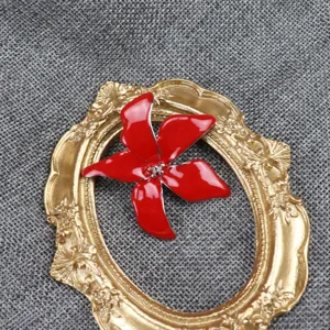 Close-up detail of a red enameled iris flower brooch, showing delicate petal texture.