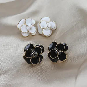 Camellia enamel flower earrings detail shot, elegant black and white design with gold trim.