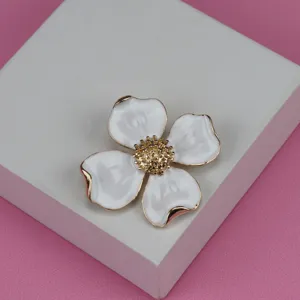 Close-up view of a vintage metal floral brooch with white enamel petals and gold stamen.