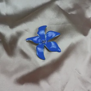 Blue enamel iris flower brooch pin, elegant clothing accessory detail for stylish outfits.