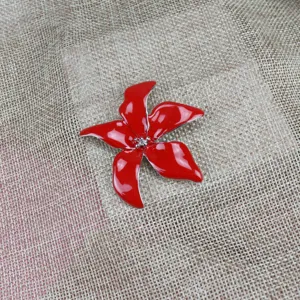 Red enamel flower brooch detail view showing glossy finish and metal edge design features.