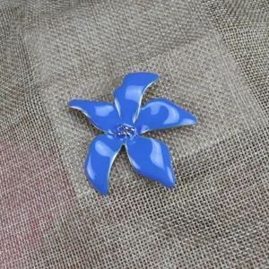 Close-up of a vibrant blue enamel iris flower brooch with metallic silver edges and delicate pistil beads.