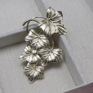Vintage gold tone grape leaf brooch jewelry detail shot showcasing delicate metallic leaf texture.