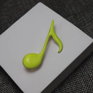 Close-up detail of a bright green enamel musical note brooch, elegant fashion accessory.