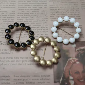 Close-up of enamel bead circle brooches in black, white, and gold, elegant accessory detail.