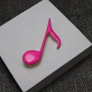 Close-up of hot pink enamel musical note brooch detail shot, perfect for clothing decoration.