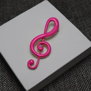 Pink enamel treble clef brooch close up view, elegant music note pin detail for apparel decor.