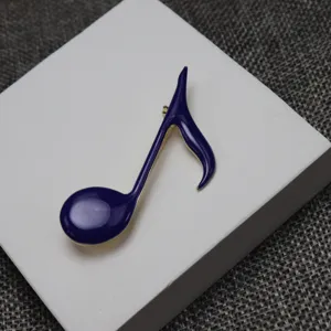 Handcrafted blue enamel musical note brooch detail shot, stylish clothing accessory for students.